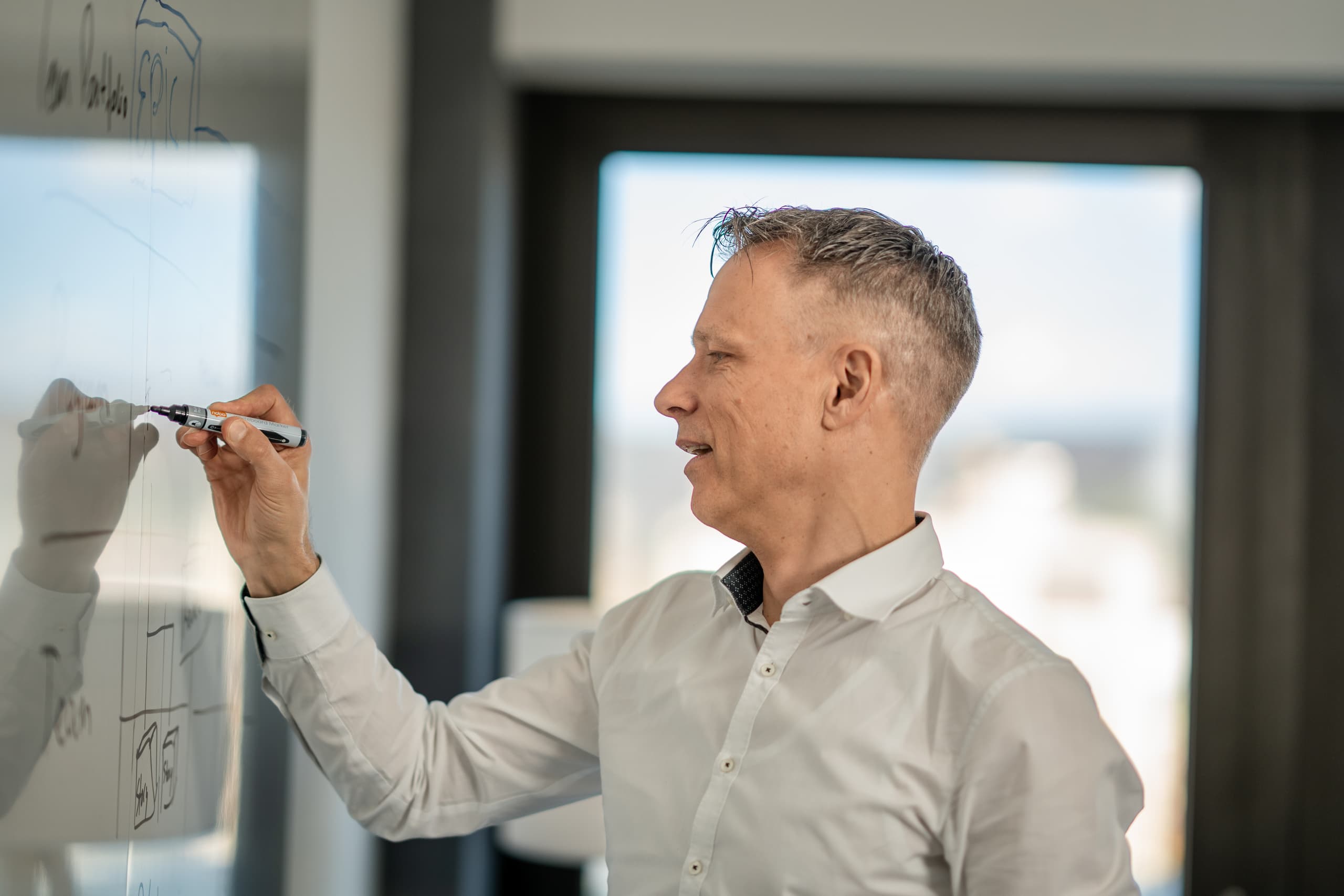 Mitarbeitender schreibt auf Whiteboard im Konferenzraum eines Bürogebäudes